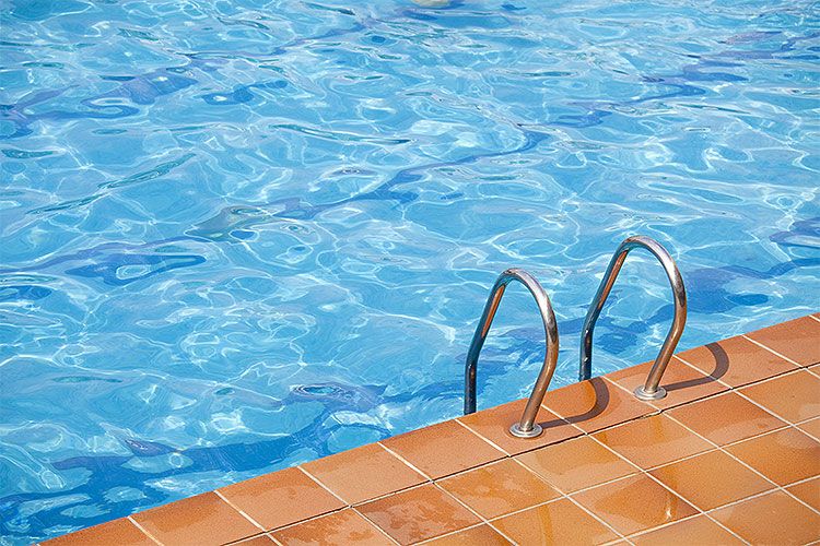 Ein Schwimmbad mit Leiter und braunen Fliesen